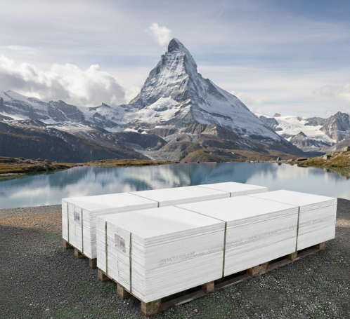 Weiße Gipskartonplatten auf Palette stehen vor einem Bergsee und dem Matterhorn.